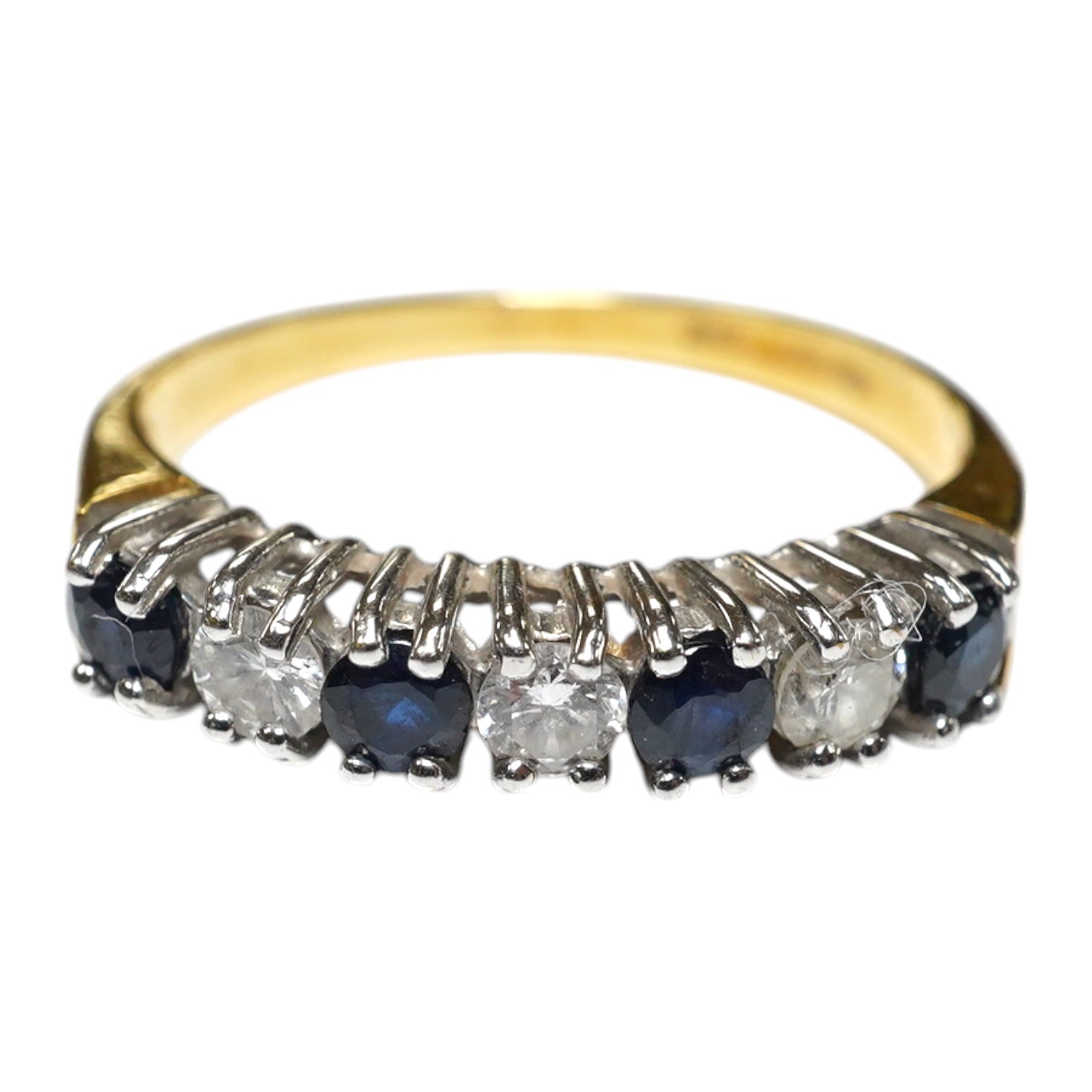 A modern 18ct gold, four stone sapphire and three stone diamond set half hoop ring, size L/M, gross weight 2.4 grams. Condition - fair to good